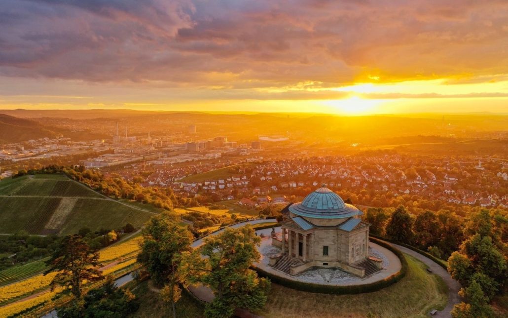 Eine Luftaufnahme von Stuttgart und einer Kirche bei Sonnenuntergang, die die faszinierende Schönheit städtischer Landschaften zeigt.