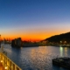 Ein Kreuzfahrtschiff legte bei Sonnenuntergang in einem Hafen an, mit den Stränden von Barcelona im Hintergrund.